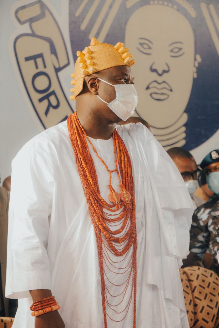 About A man in traditional Nigerian attire with beads and a mask at a cultural event.