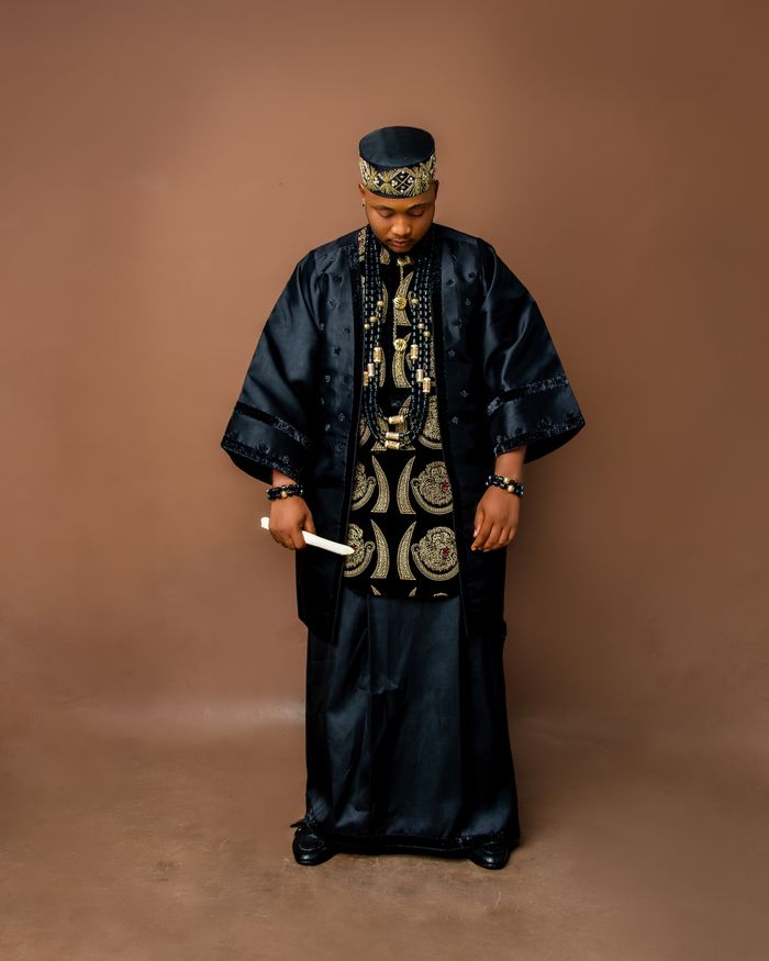Services Man in traditional Nigerian attire, standing against a neutral background.