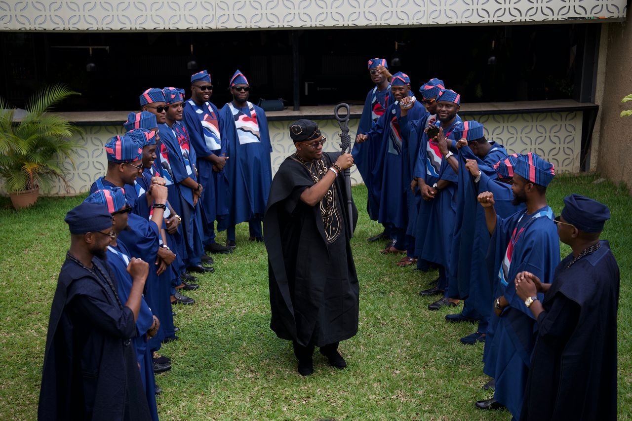 Services Nigerian groom surrounded by groomsmen in traditional agbada in Abuja, showcasing vibrant African men's fashion.